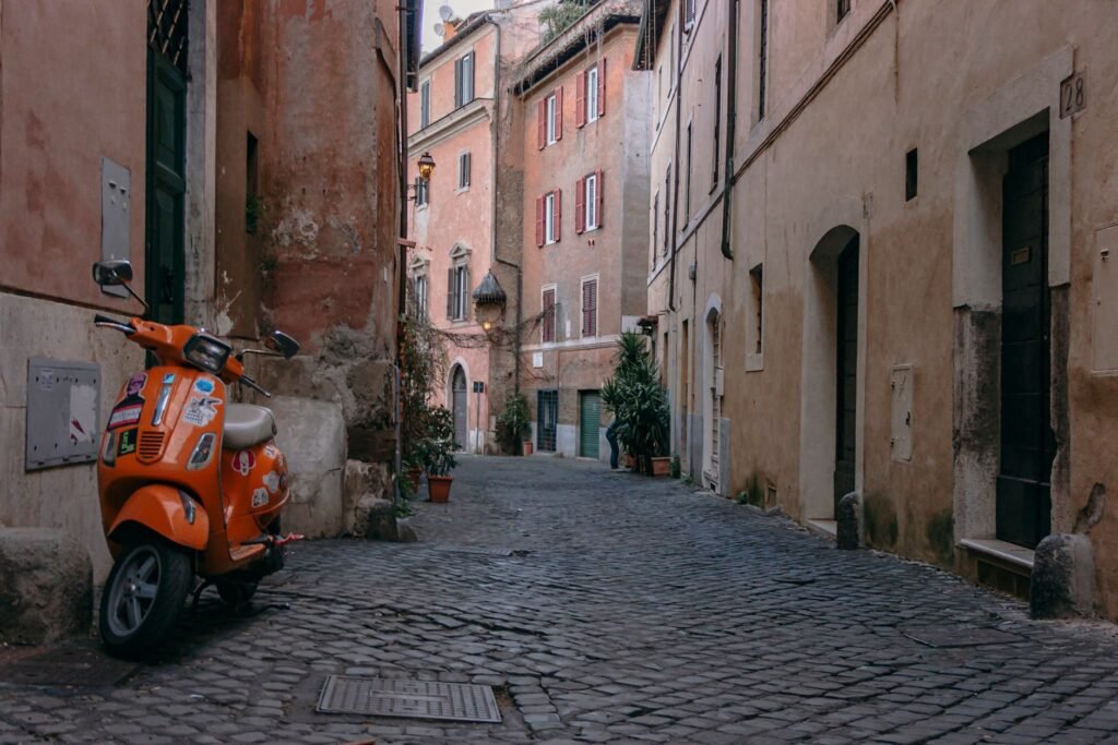 A quiet cobbled lane in Trastevere, Rome, with a parked scooter